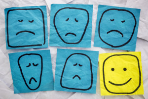 a set of sad, unhappy and happy, smiling faces - rough sketches on isolated blue and yellow sticky notes