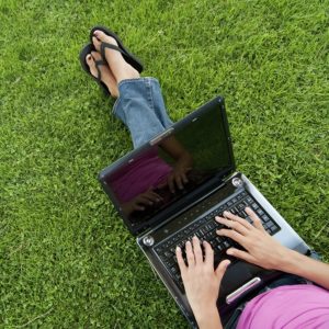 Woman with laptop sit relaxed green grass