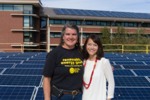 Colorado State University Facilities Engineer Carol Dollard and Housing and Dining Services Director of Communications Tonie Miyamoto pose as a solar array is installed on the roof of Braiden Hall, October 24, 2014.
