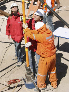 Workers sending communications cable down a mine shaft.