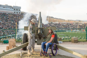 Amy Van Dyken in wheelchair with cadet firing cannon.