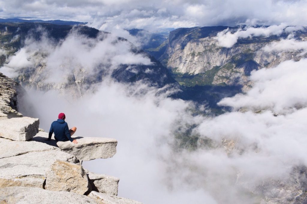 person sitting on cliff at Yosemite National Park