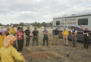 group of individuals standing in a circle outside a mobile command center