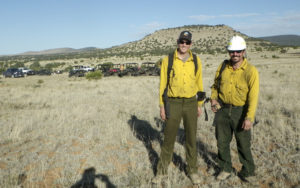 two men dressed in wild land fire fighting gear outdoors