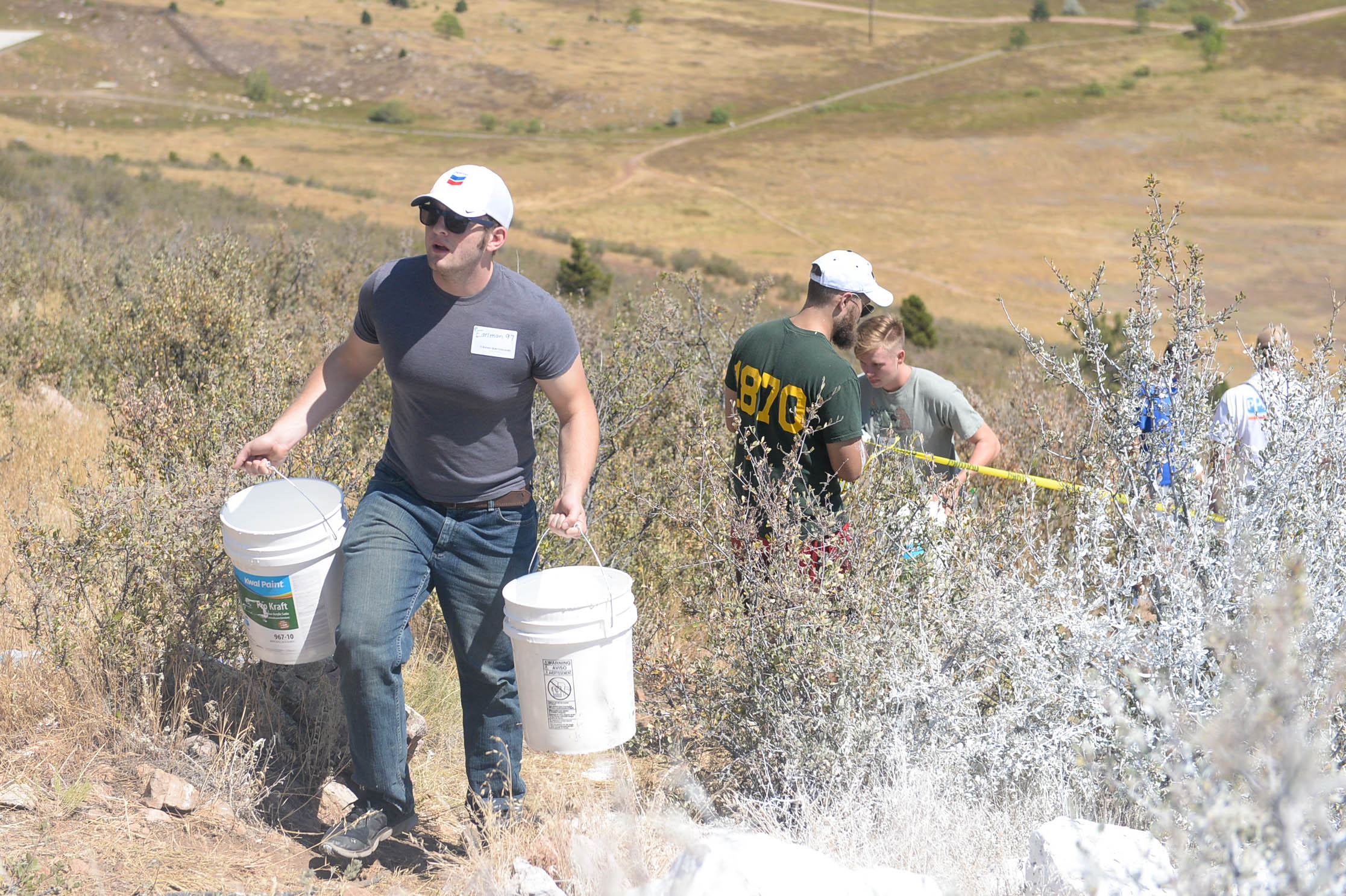 Students carrying bucket of paint up a hill