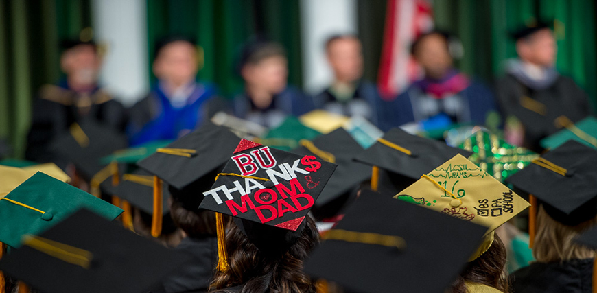 Graduation caps at College of Veterinary Medicine and Biomedical Sciences. One reads "BU Thank$ Mom & Dad"