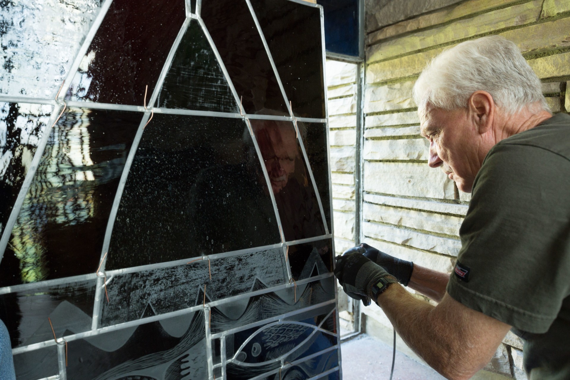 Workman installing stained glass window in Danforth Chapel