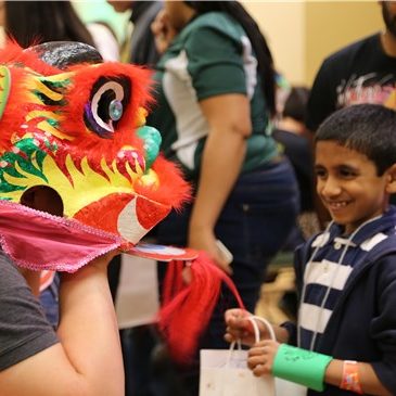 Small boy smiles at CSU student in dragon mask