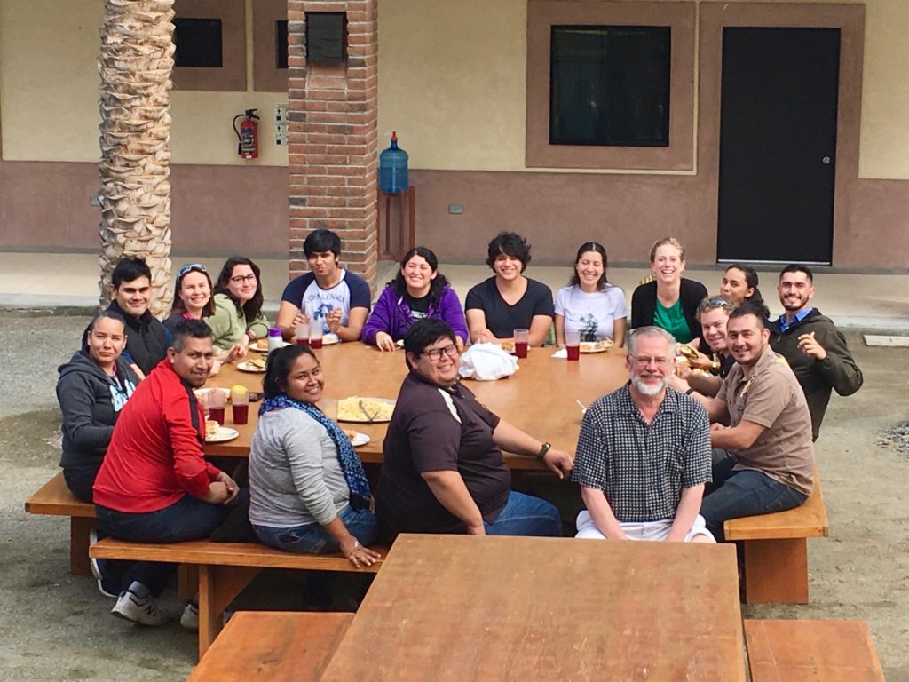 Group photo of fish pathology workshop participants around a table outside.