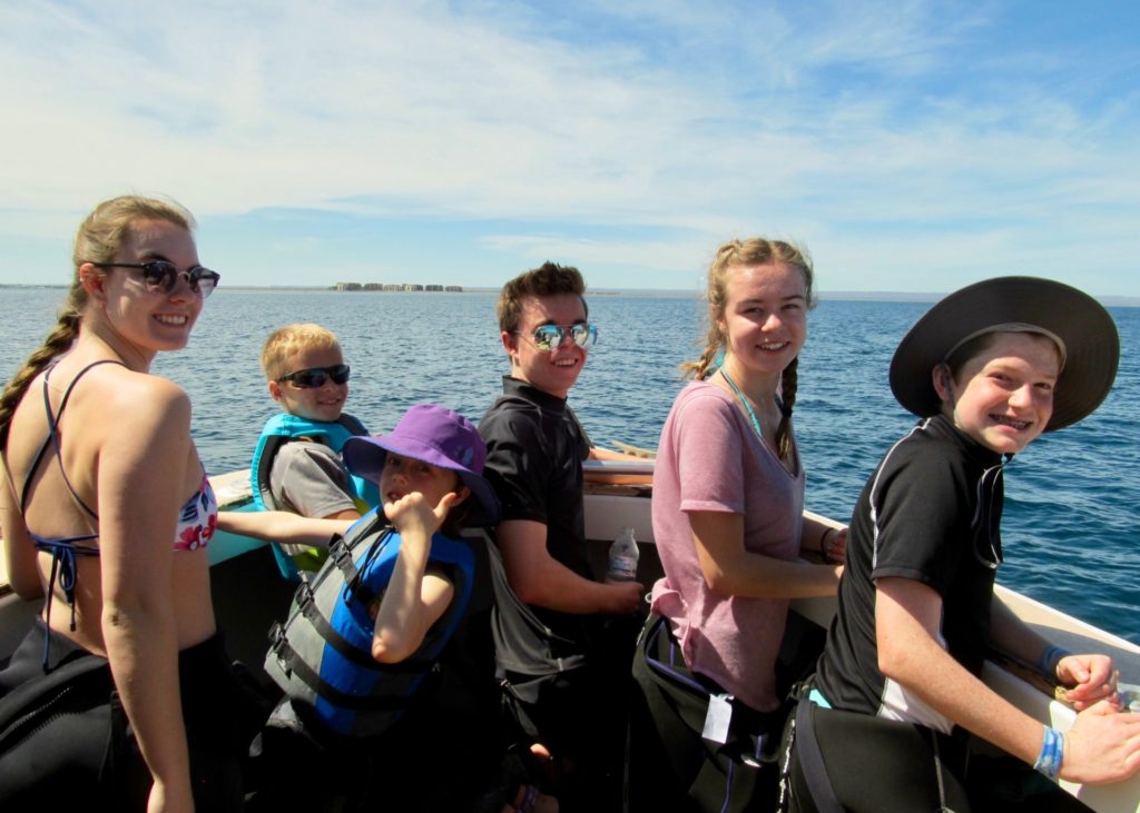 Five Todos Santos Center Family Adventure Week participants smiling from boat.