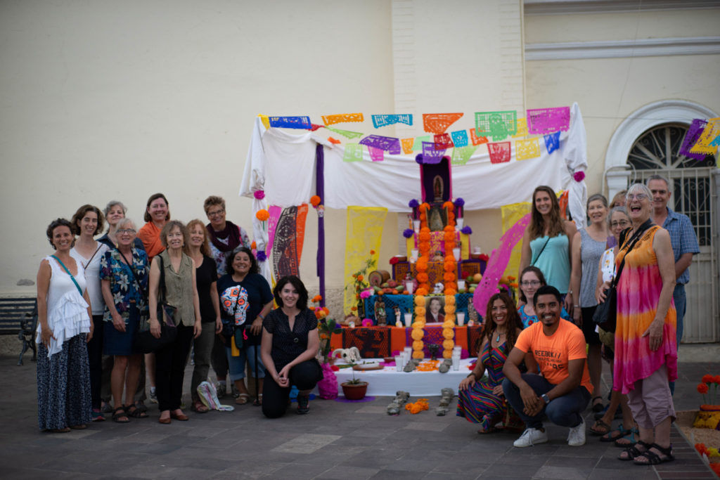 Participants of the 2018 Spanish & Culture Immersion Program at the CSU Todos Santos Center pose for group photo in front of Dia de Muertos altar.
