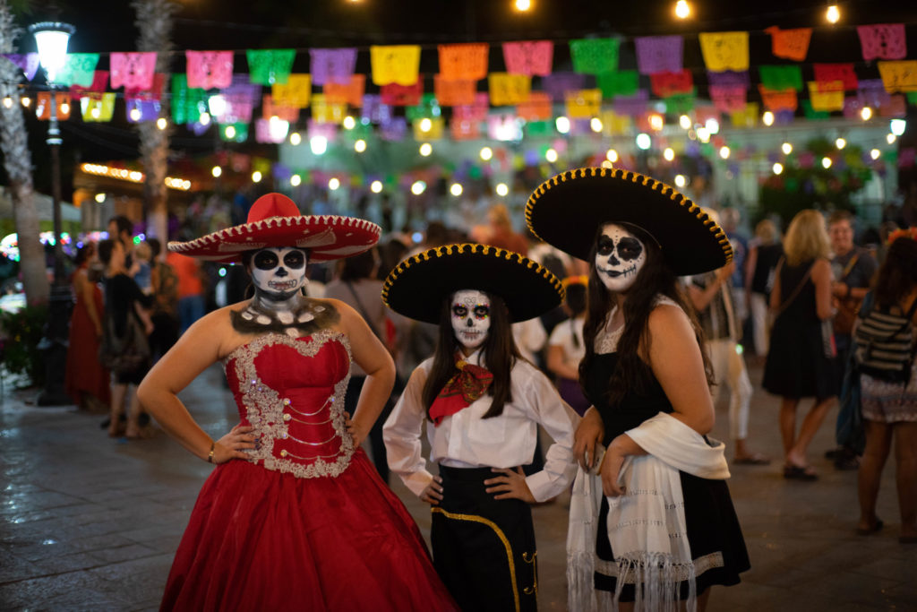 Mexican girls dressed in traditional Dia de Muertos attire pose for photo during celebration near the CSU Todos Santos Center as part of closing ceremony for 2018 Spanish & Culture Immersion program.