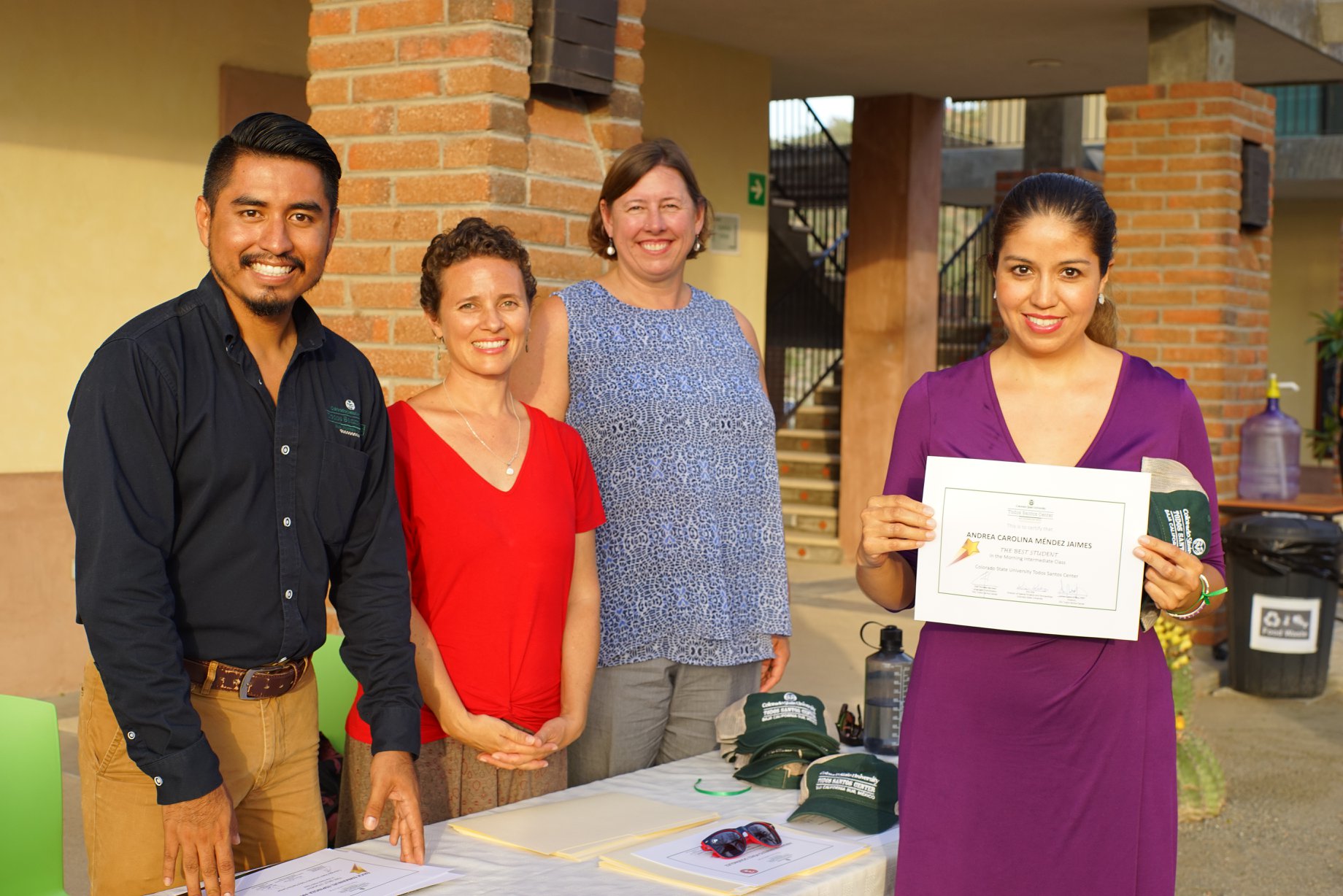 Personal de CSU Todos Santos Center (desde la izquierda: Olaf Morales, Aines Castro y Kim Kita) con la estudiante de inglés y residente de BCS Andrea Carolina Méndez Jaimes durante la ceremonia de graduación de 2018.