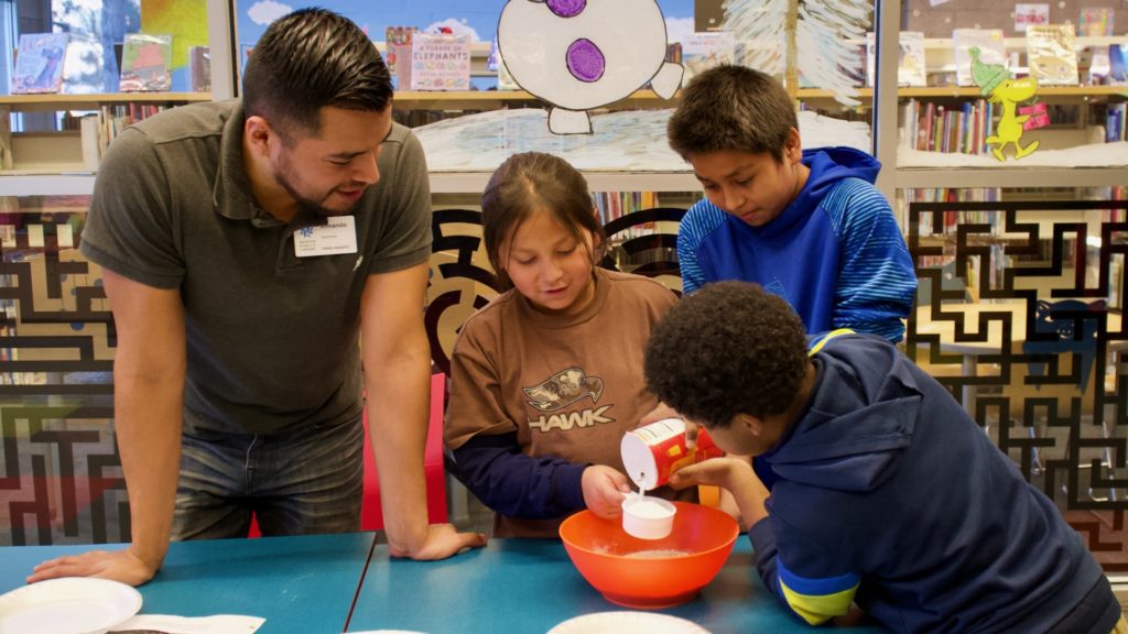 Library Program Associate Armando Pineche Rosales (far-left) engages youth participants during a STEM workshop on entomology led by CSU Denver Extension/4-H Agent Merielle Stamm (not pictured) at Valdez-Perry Branch Library in north Denver.