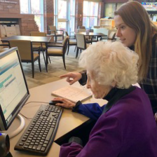Young person helping older woman with computer