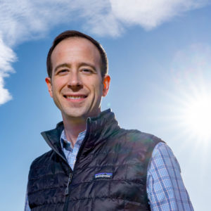 researcher Nathan Mueller under a blue sky with clouds