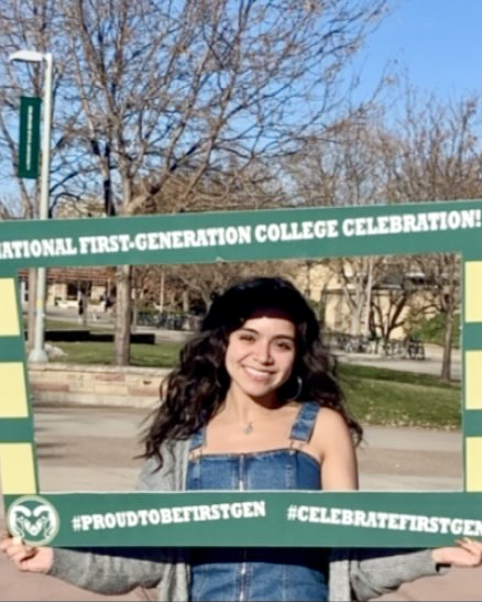 CSU student Jilda Nevarez holding a National First-Generation College Celebration social photo frame outside, on campus during sunny day.