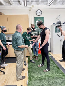 Students set up sensors and markers on Michael Boyle that will be read by their software as part of the foot-turf interaction study.