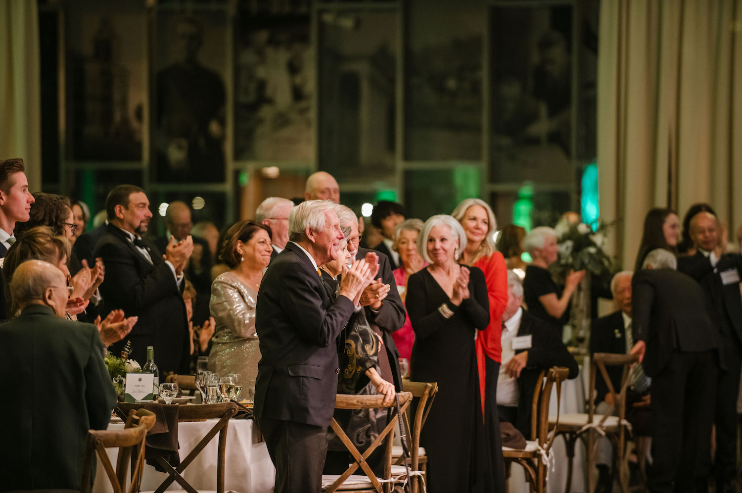 People stand and clap at a dinner event.