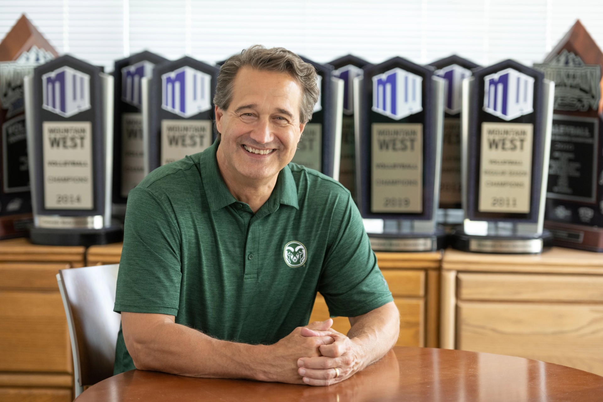CSU volleyball coach Tom Hilbert in front of some of the program's trophies.