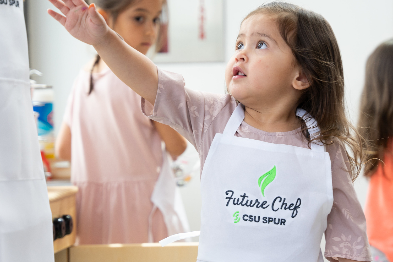 A young girl wears an apron that says "future chef."