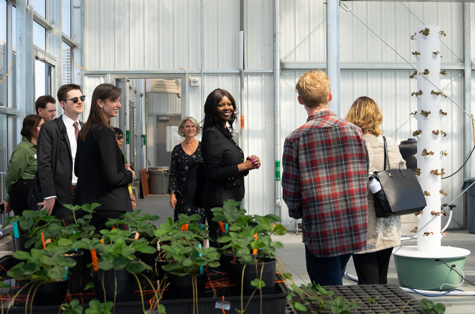People stand and talk in a greenhouse.