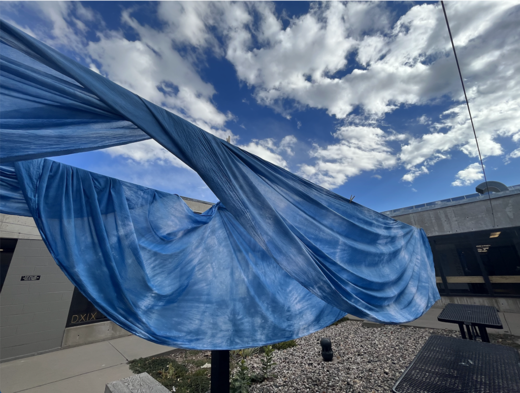 Indigo dyed fabricx hangs from a drying line.