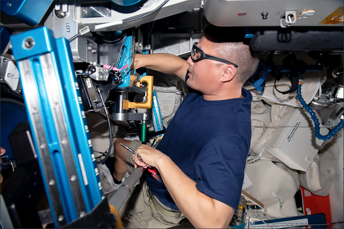 Kjell Lindgren performs maintenance on the advanced resistance exercise devise (ARED) aboard the International Space Station.