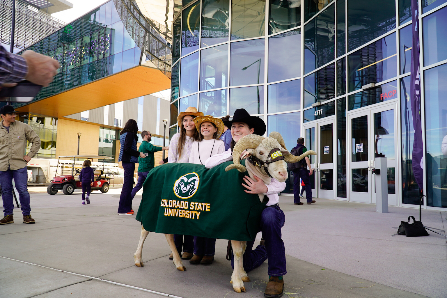 A group stands next to a ram wearing a CSU blanket.
