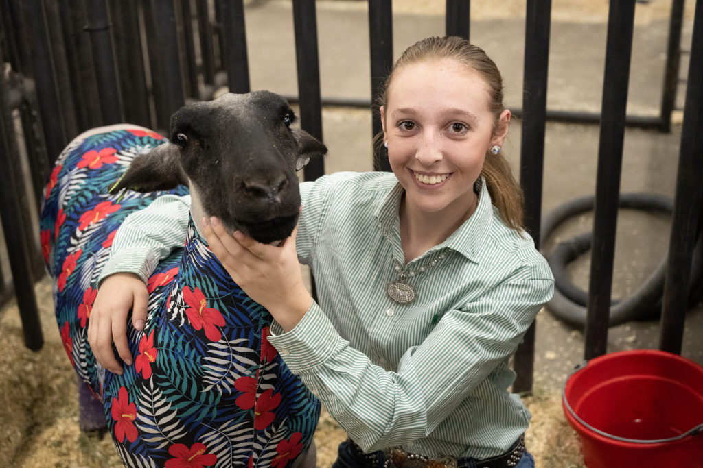 Lexi Vrabec poses for a photo with her sheep in a livestock pen