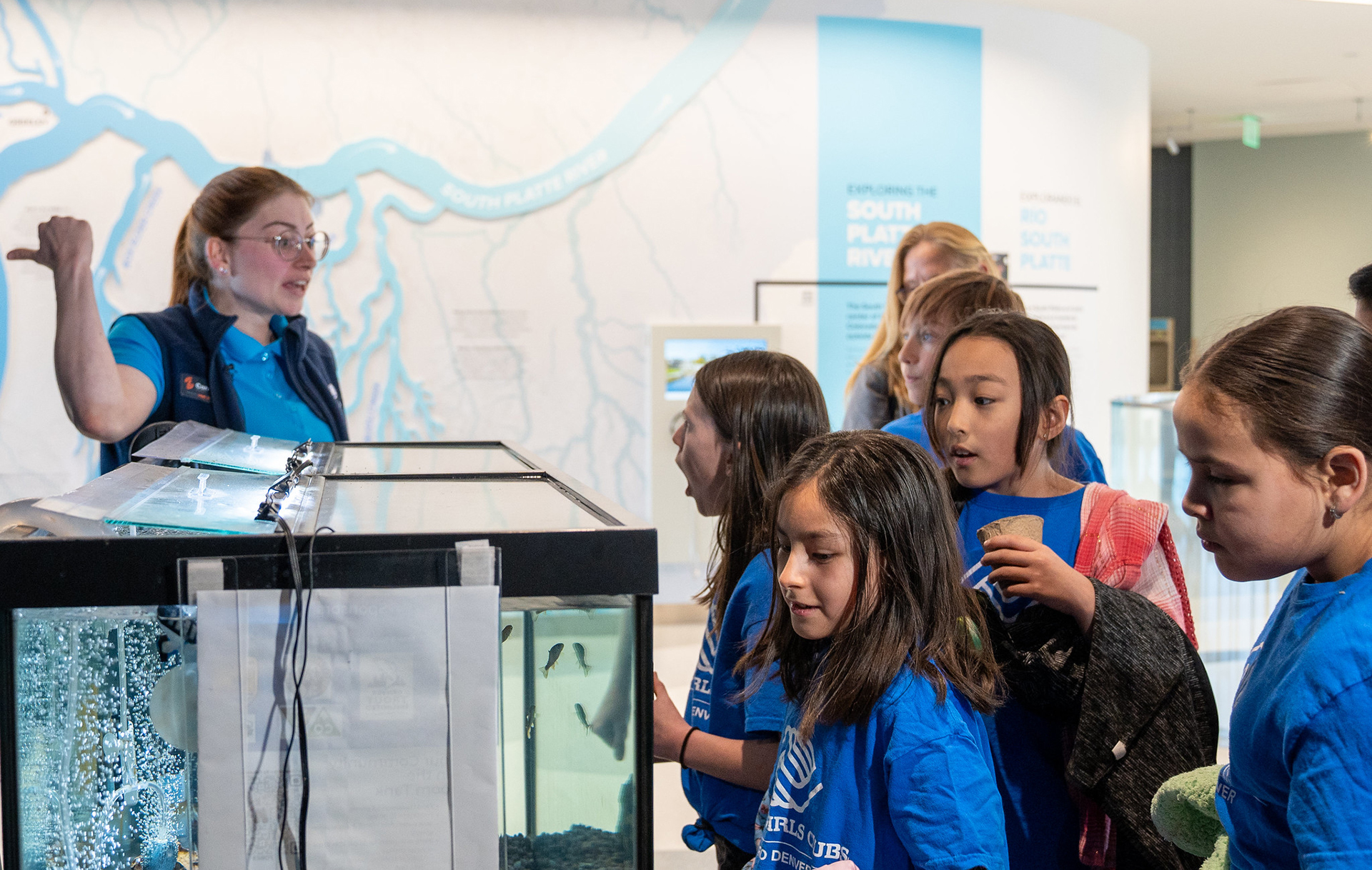 Children watch fish in an aquarium as a tour guide talks to the group from Boys and Girls Clubs of Metro Denver.