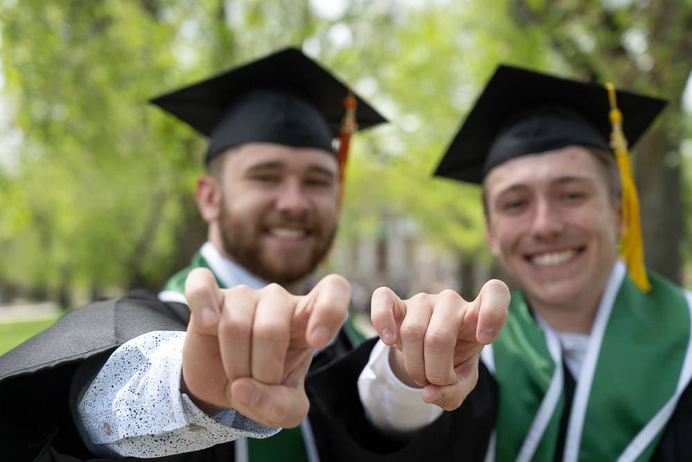Two grads making the CAM gesture