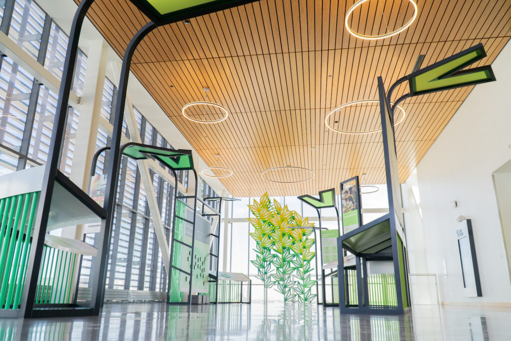 Interior of a building with exhibits and a hanging piece of green and yellow abstract art.