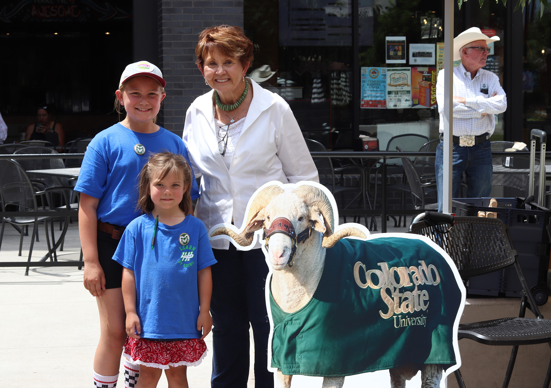 A woman poses for a photo with two 4-H youths next to a cardboard cutout of CAM the Ram, CSU's mascot