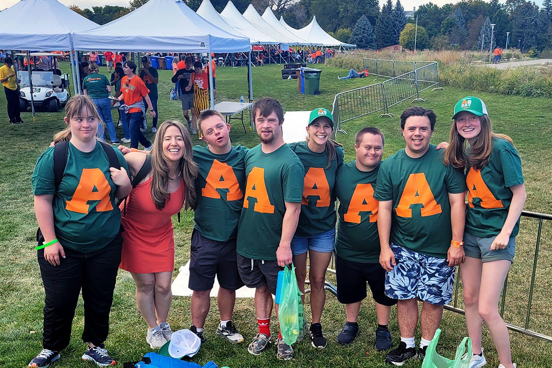 Some of the RAM Scholars, their mentors and the co-director of the program pose in a line in front of tents during Ag Day when the Scholars helped serve food.