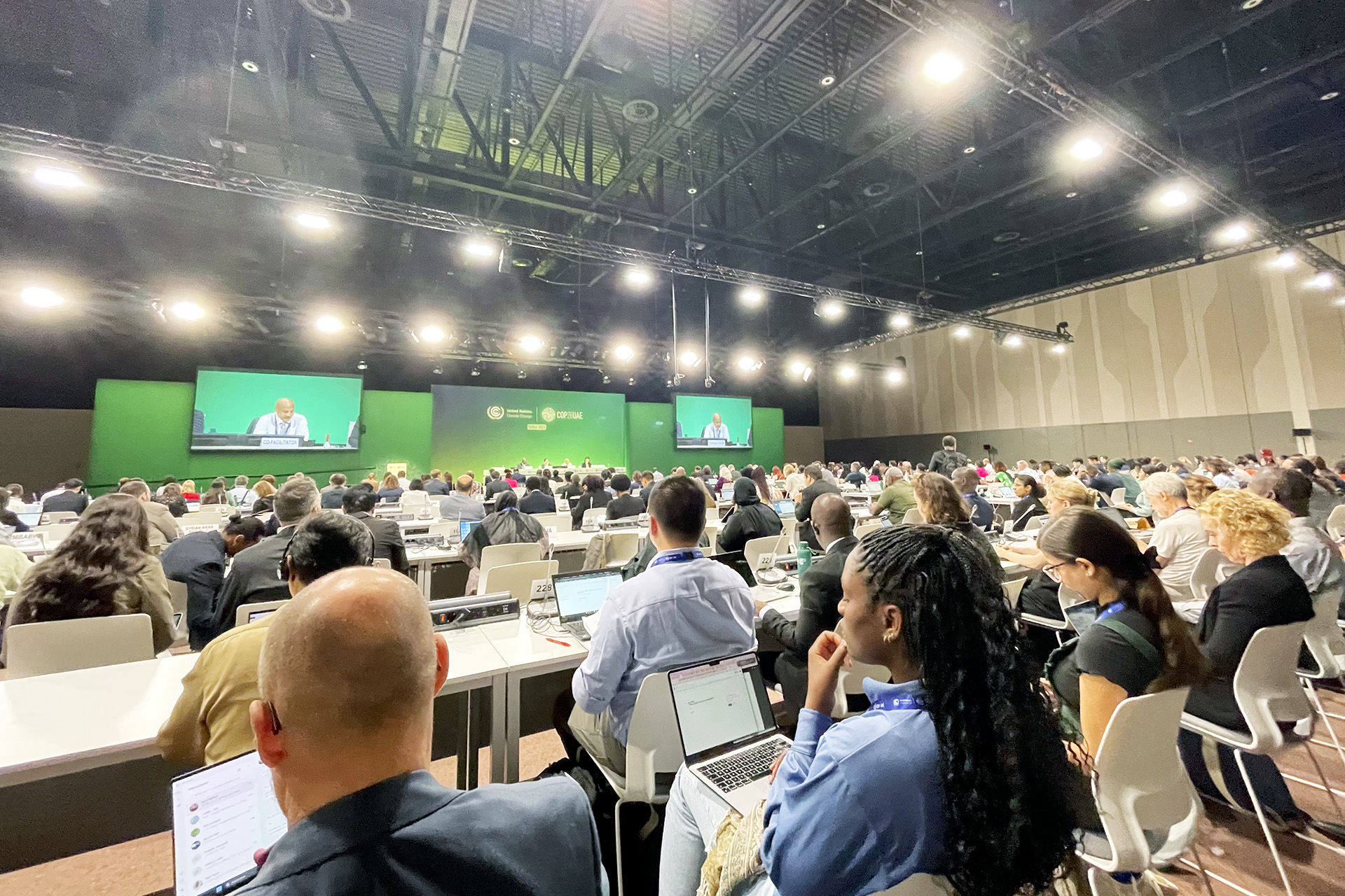 Attendees of COP28 in Dubai are packed into a gymnasium-sized room to view presentations.