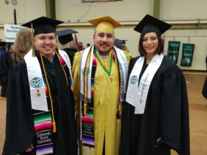 Three students wearing graduation garb during First Gen Commencement.