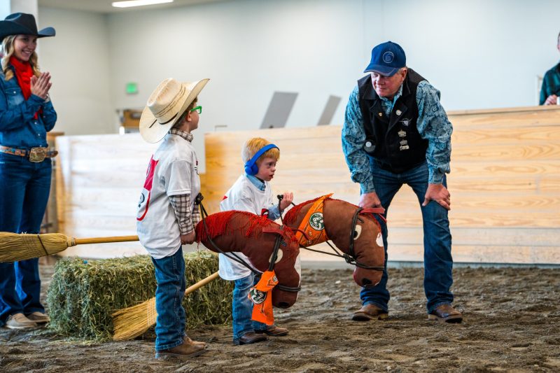 A kid rides a toy horse at the Exceptional Rodeo